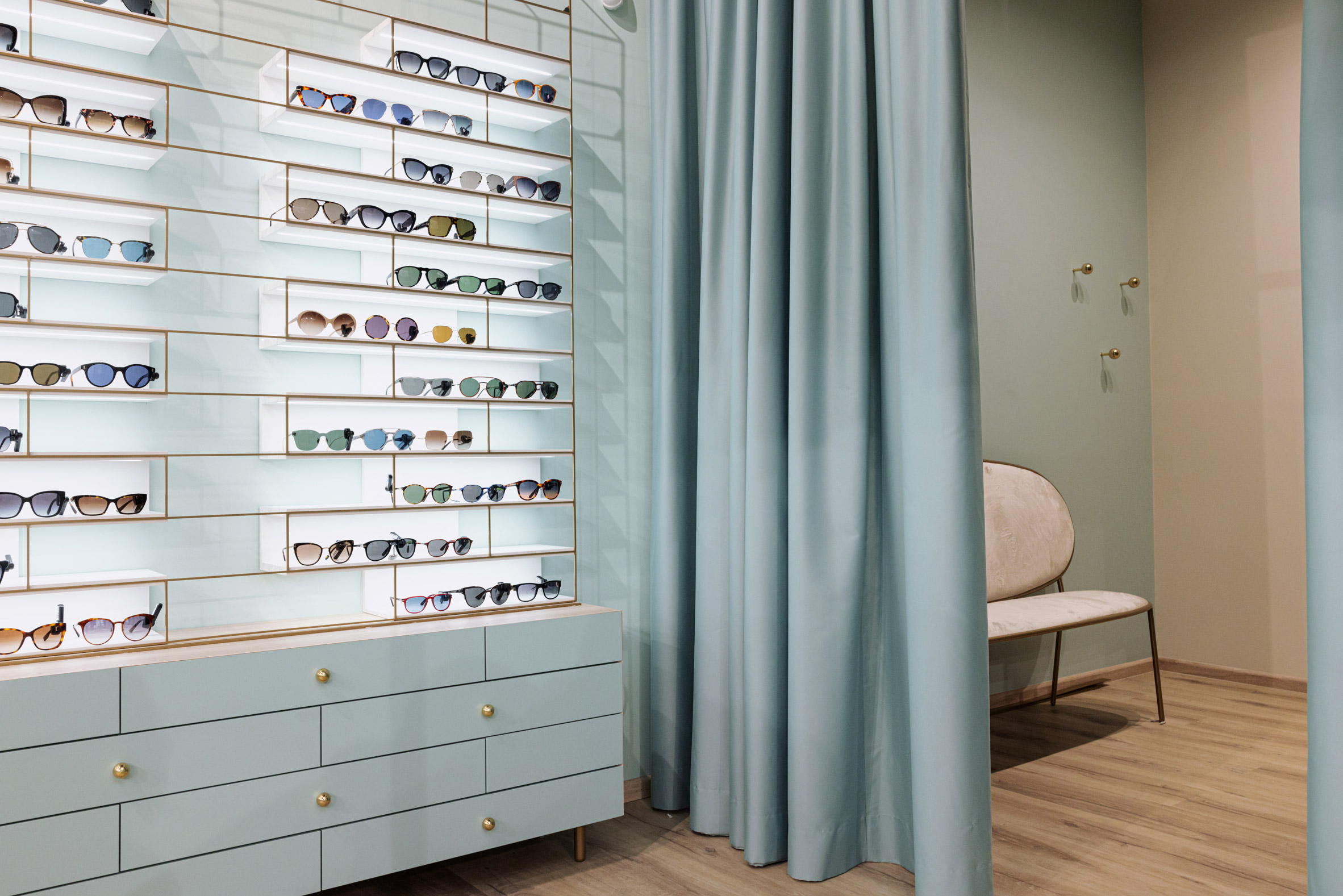 Blue curtains dividing treatment room from glasses display inside eyewear store in Ljubljana, Slovenia, designed by Nika Zupanc