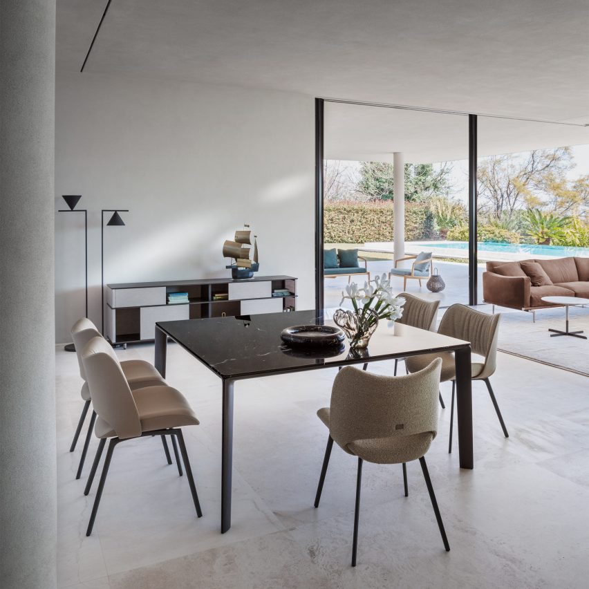 Nice chairs by Poltrona Frau around the Homey table in a concrete room with floor to ceiling glass window