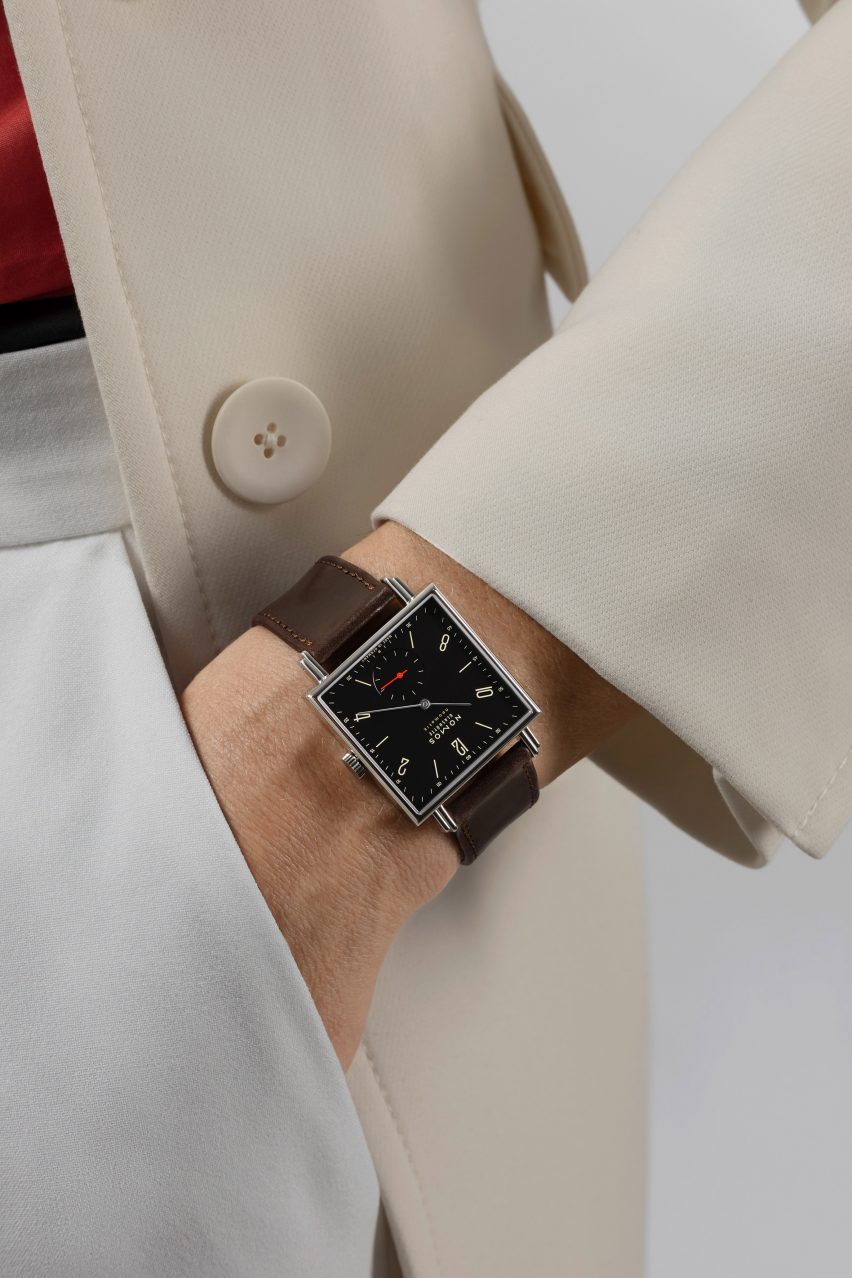 A photograph of someone wearing black watch by Nomos Glashütte