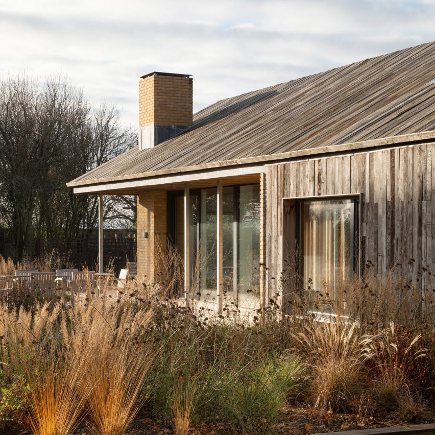 Patio corner of Pad Studio's barn house with timber cladding extending from the facade up the roof