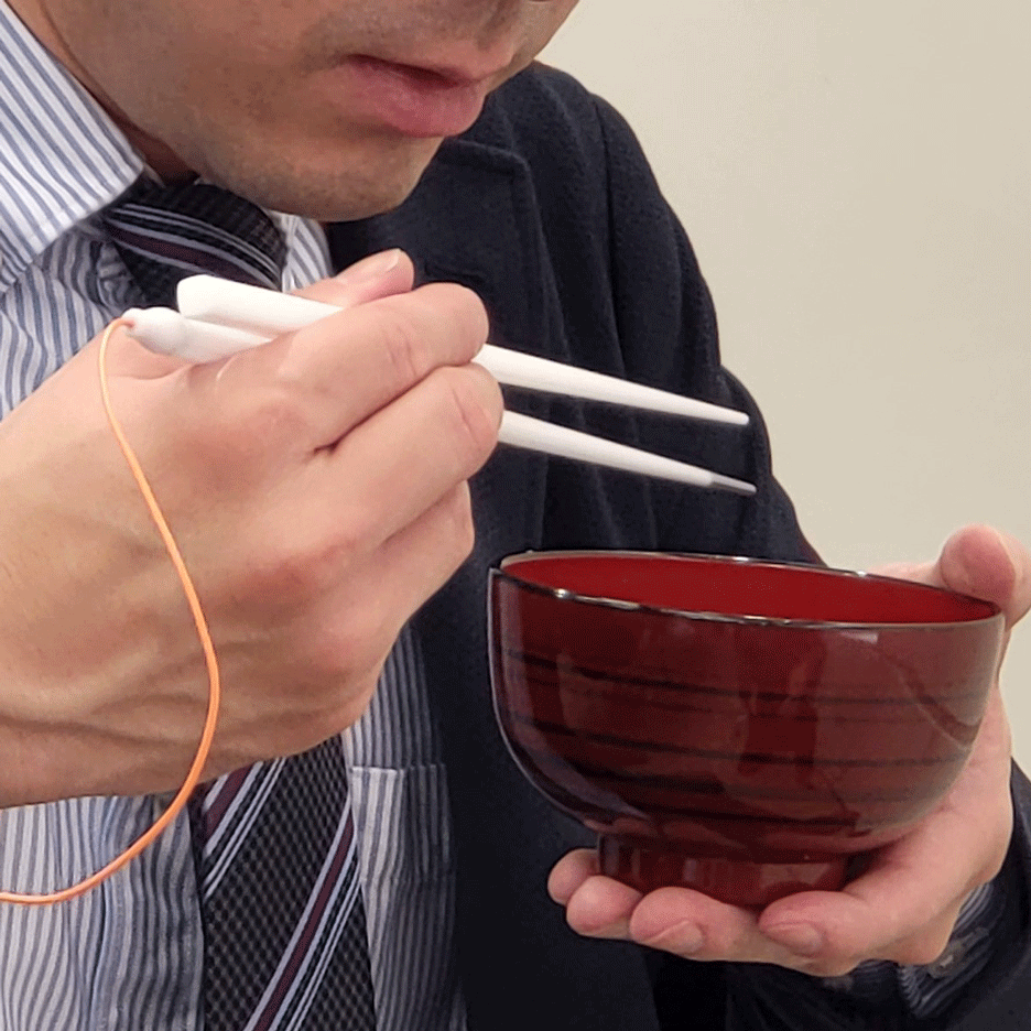 A man eating from a bowl with Taste-Adjusting Chopsticks