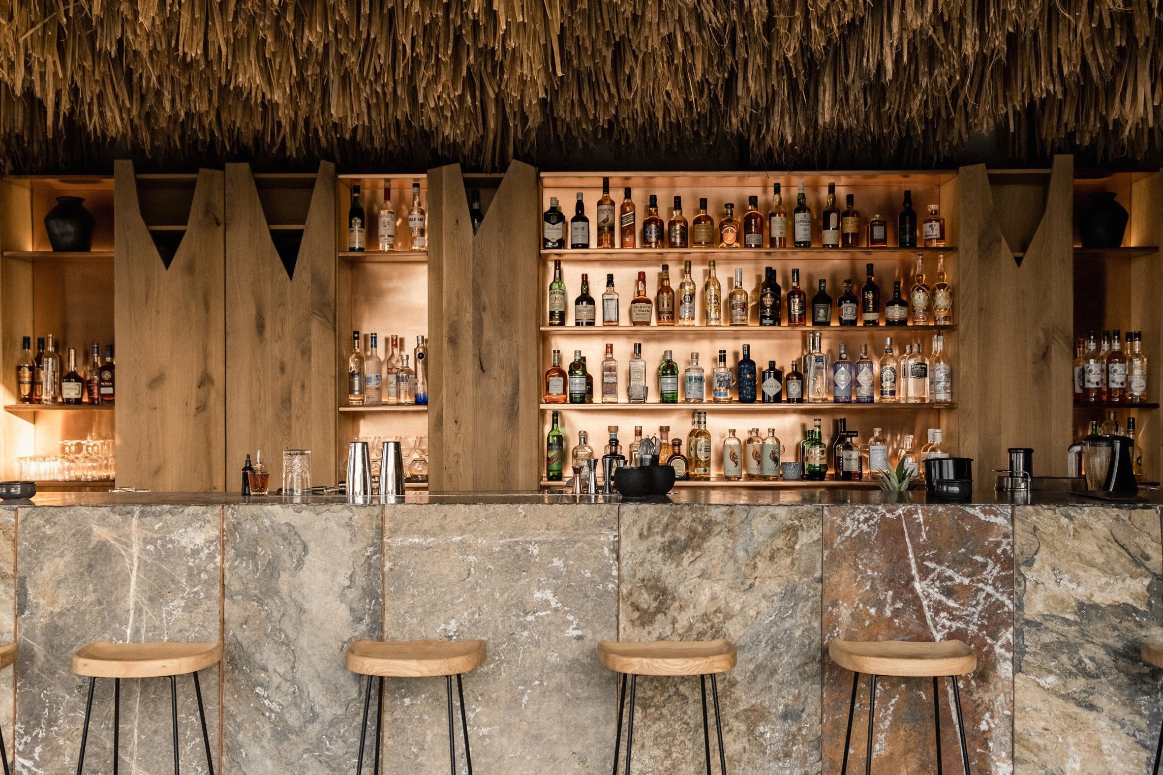 Bar with thatched roof and stone counter in Arco Suites hotel