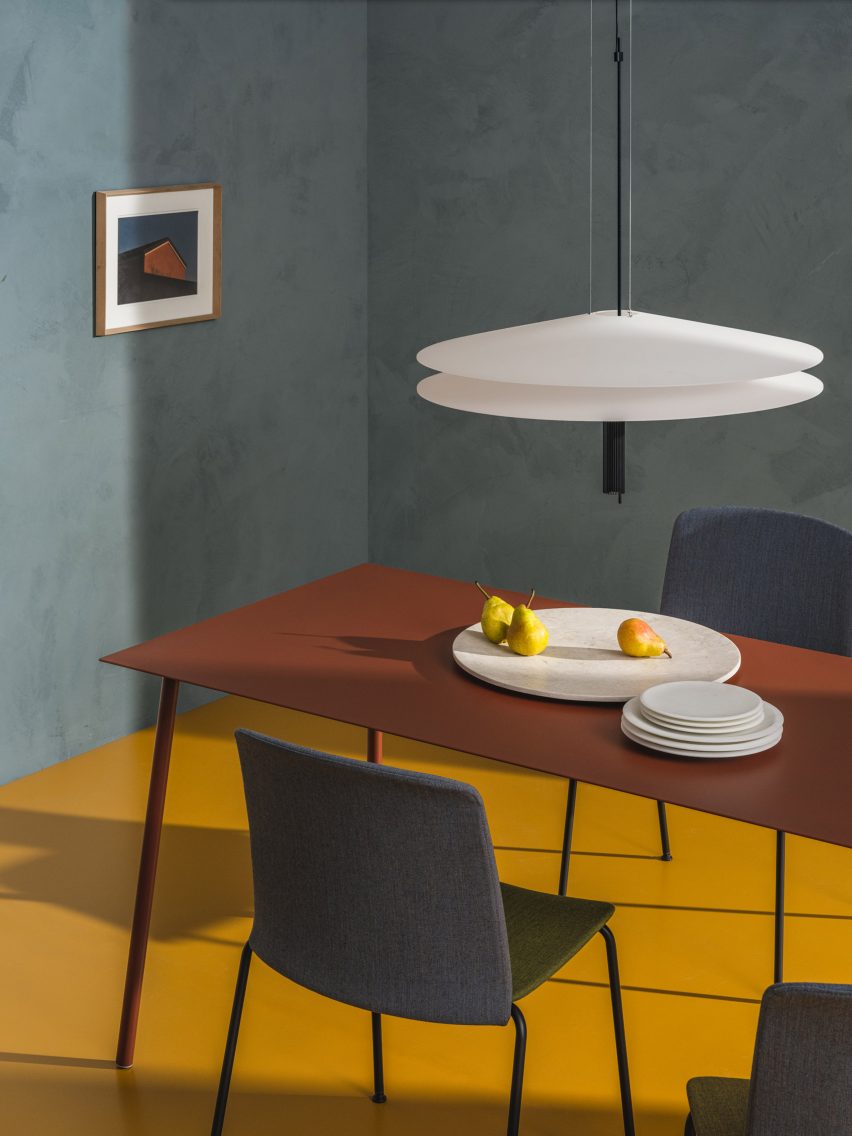 Red Aeeri dining table by Arper in a teal dining space with mustard yellow floor