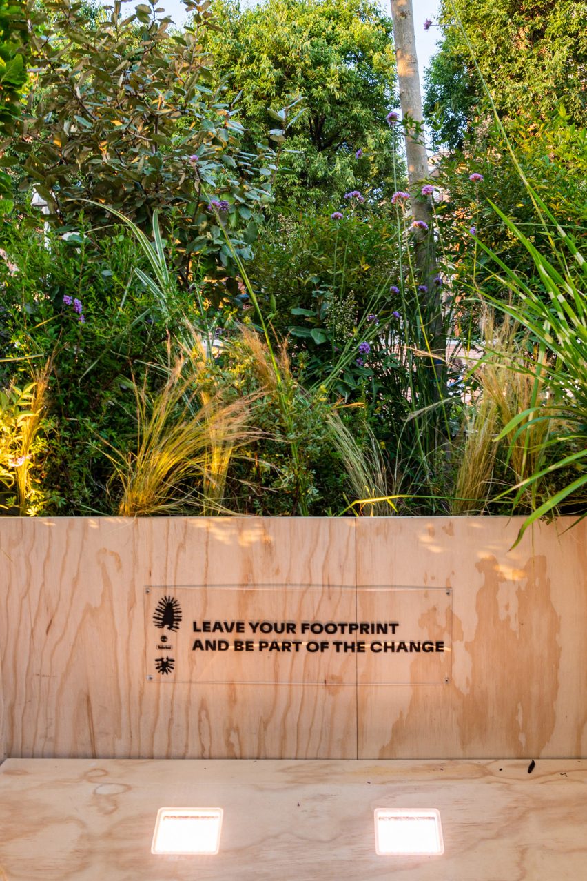Wall text on floating forest installation reads "leave your footprint and be part of the change"