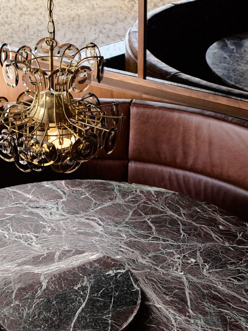 Marble table top and ornate chandelier in interior of. Jane bar