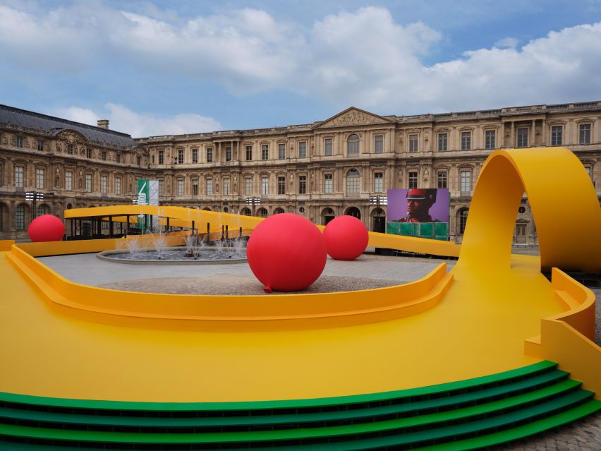 A yellow path winds through a courtyard of the Louvre during the Louis Vuitton Spring Summer 2023 show