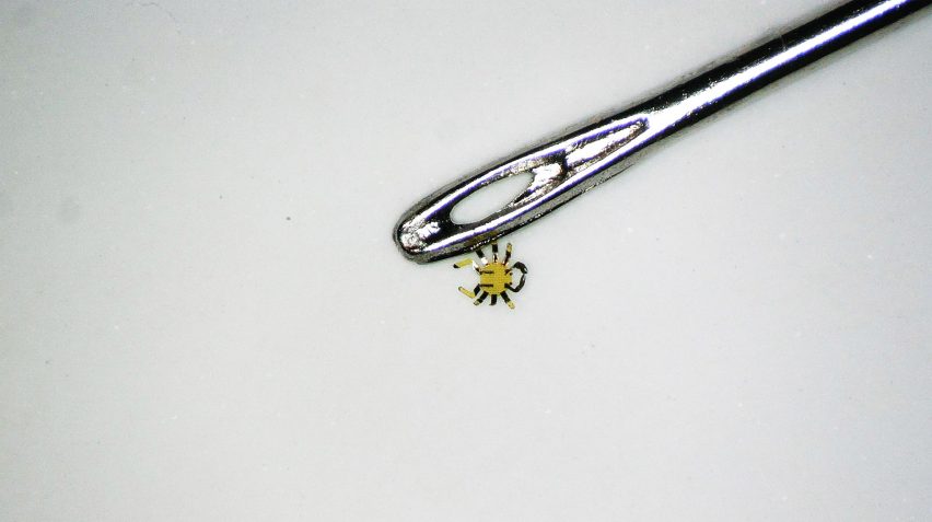 Tiny robot crab beside the eye of a needle