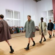 Models are pictured walking across the paper set at the Prada Spring Summer 2023 show
