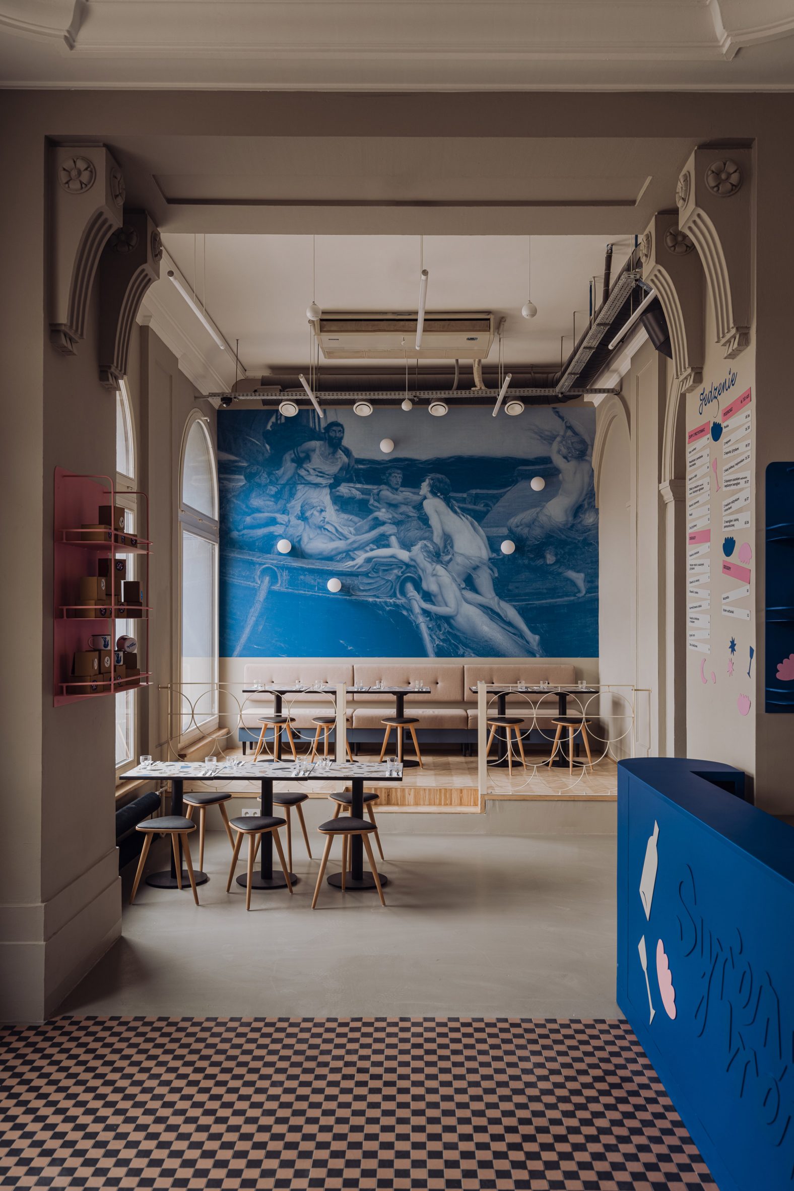 Seating area of pierogi restaurant in Warsaw by Projekt Praga with checked floor and blue details