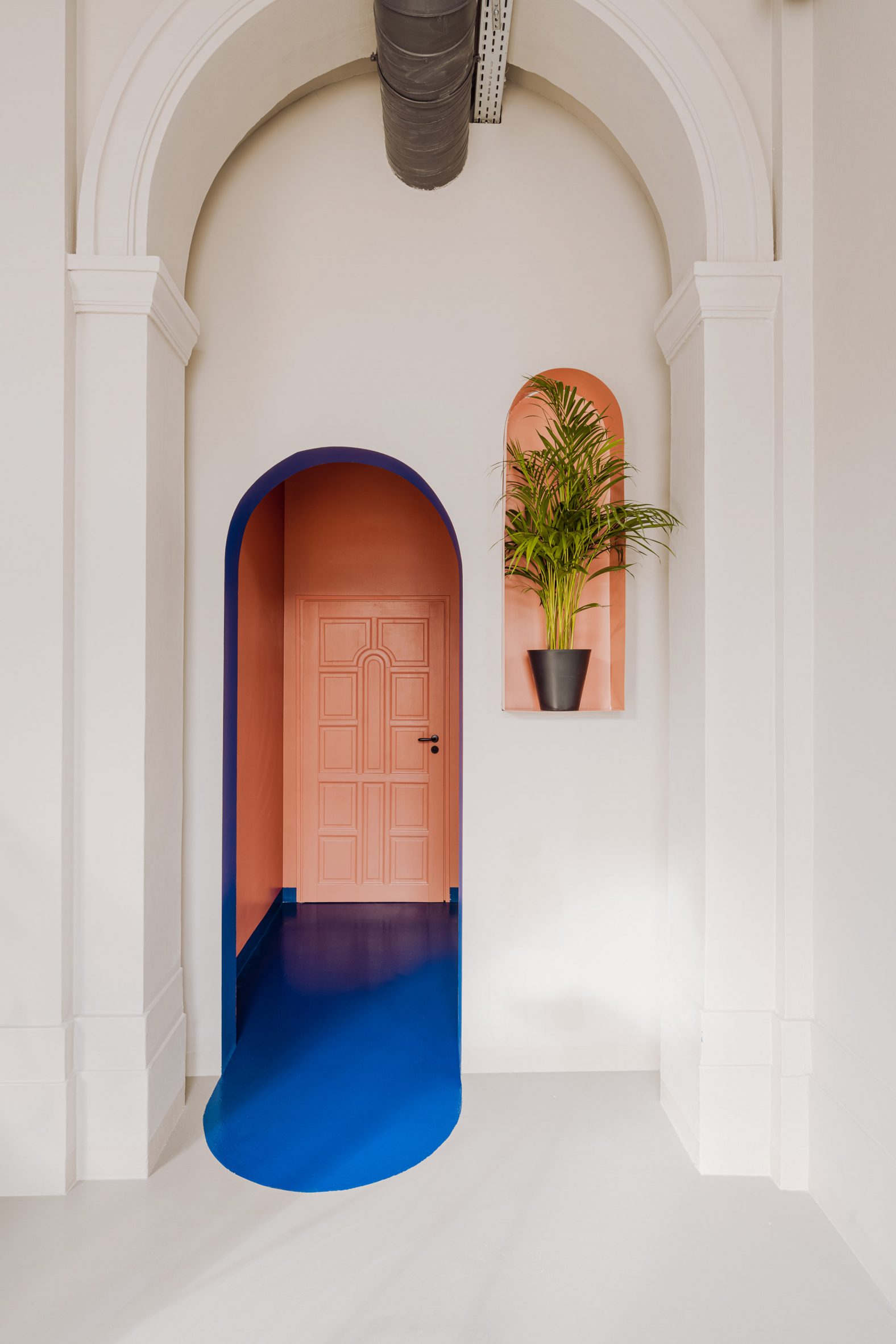 Coral and blue-coloured doorway in restaurant in Warsaw by Projekt Praga