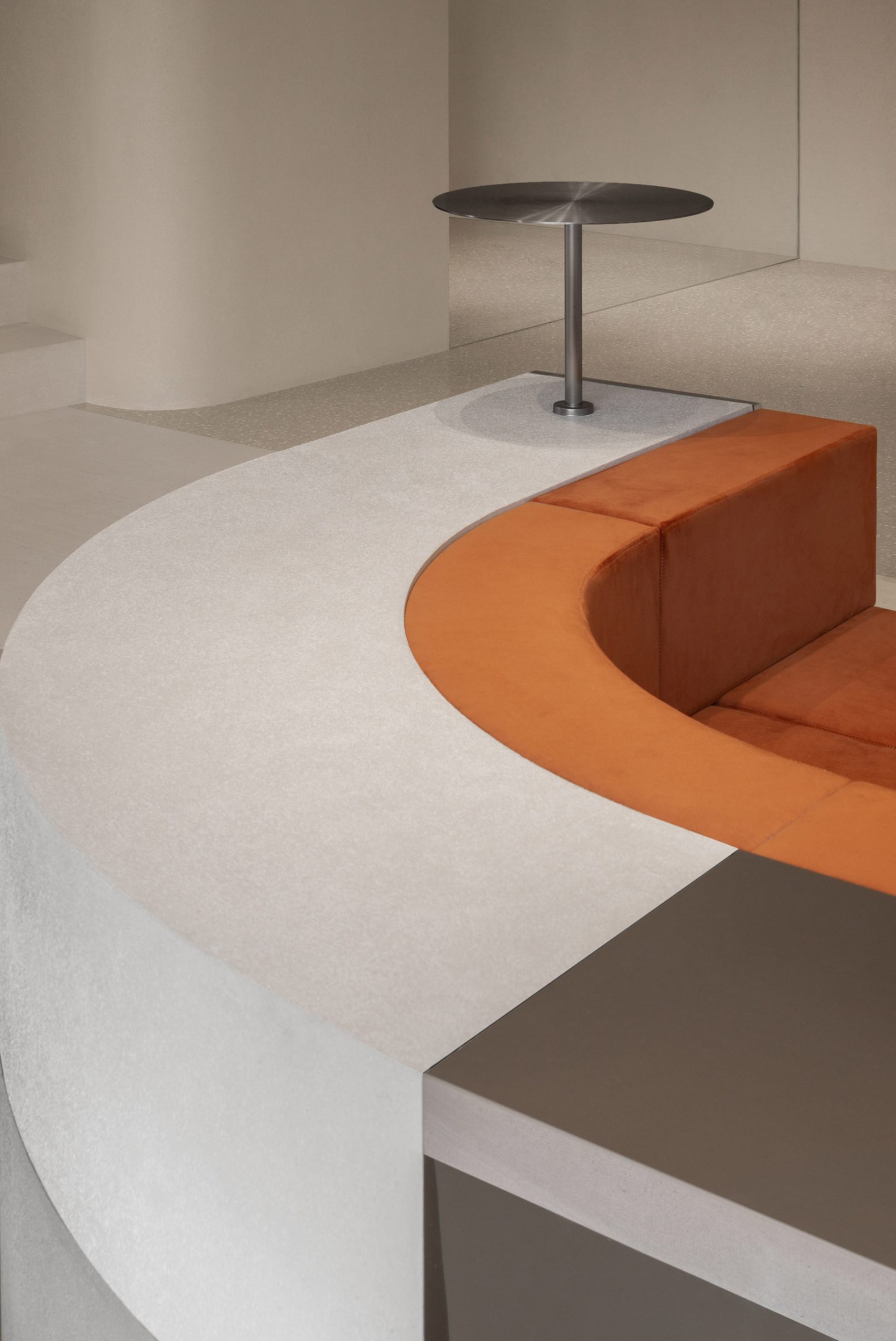 Curved bench in retail interior by Sun Concepts Office with burnt-orange cushions