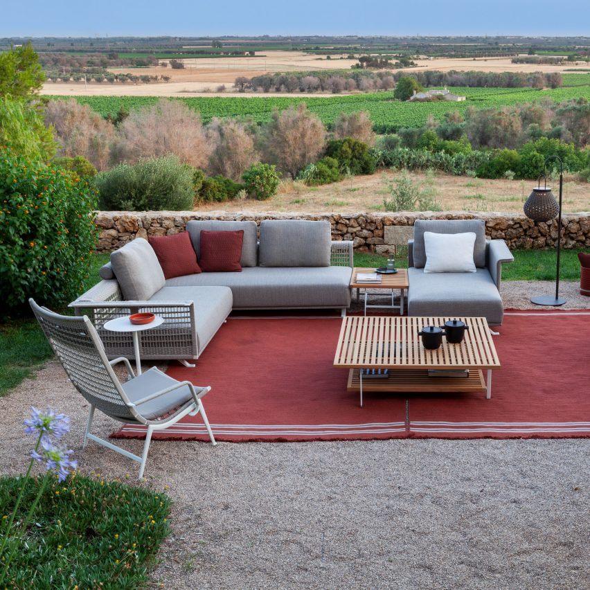 Solaria modular sofa by Poltrona Frau on a red rug outdoors with a field in the background