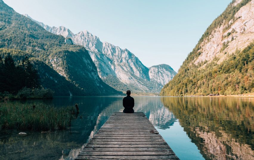 A person sitting besides a lake