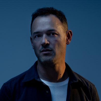 Photograph showing portrait of a man in front of navy blue backdrop