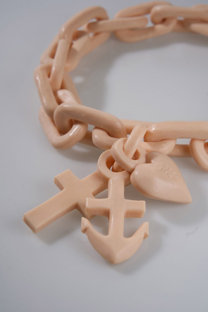 Detail of putty-coloured chunky necklace with crucifix, heart and anchor charms