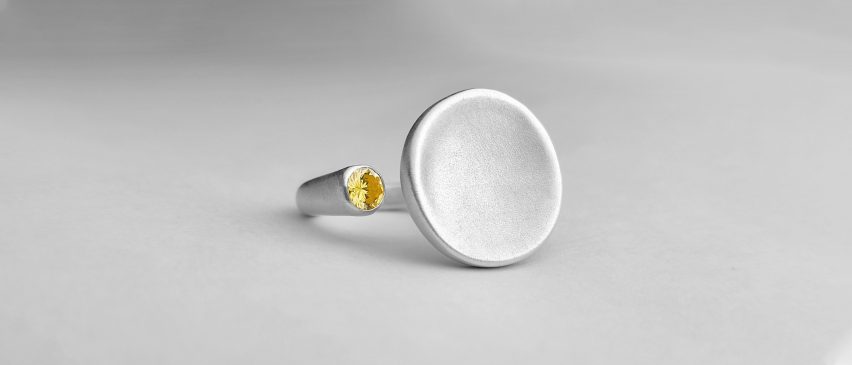 Silver ring with flat, round concave plate and small yellow jewel