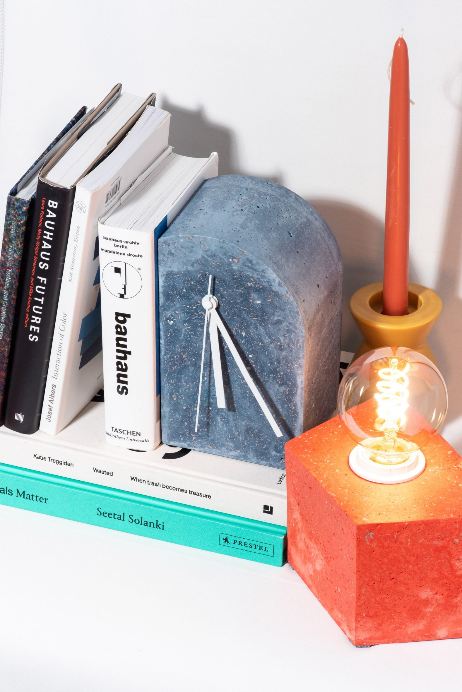 Photograph showing minimal clock amongst objects on a shelf