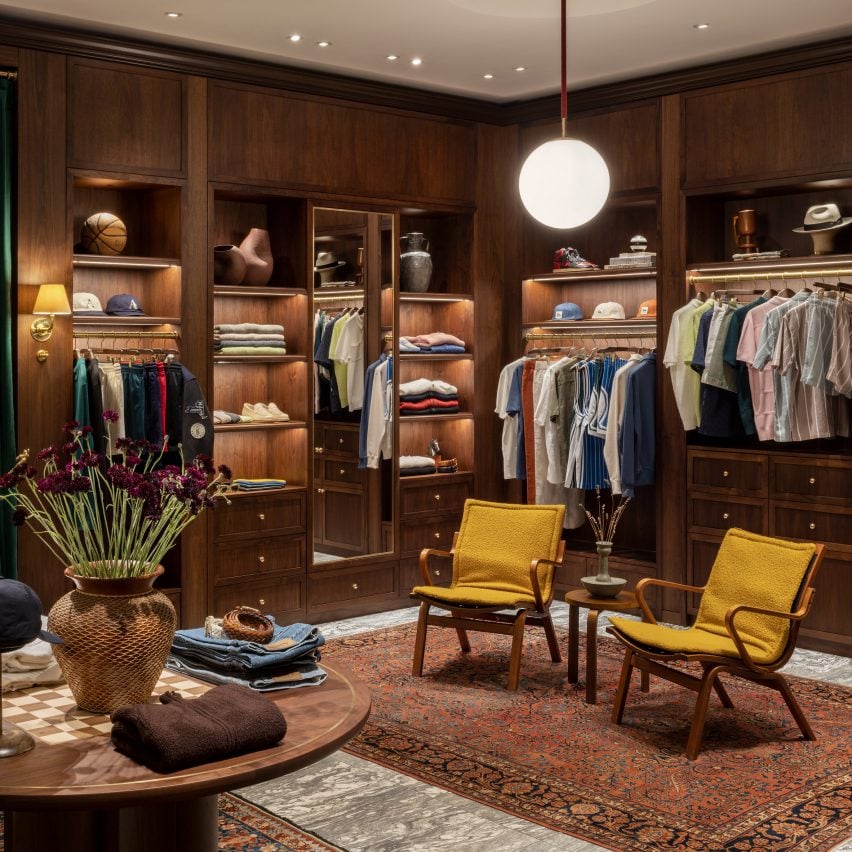 Seating area with yellow armchairs and walnut cabinetry in clothes shop in London by Sarita Posada