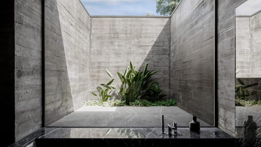 A kitchen looks out to a board-marked concrete light well