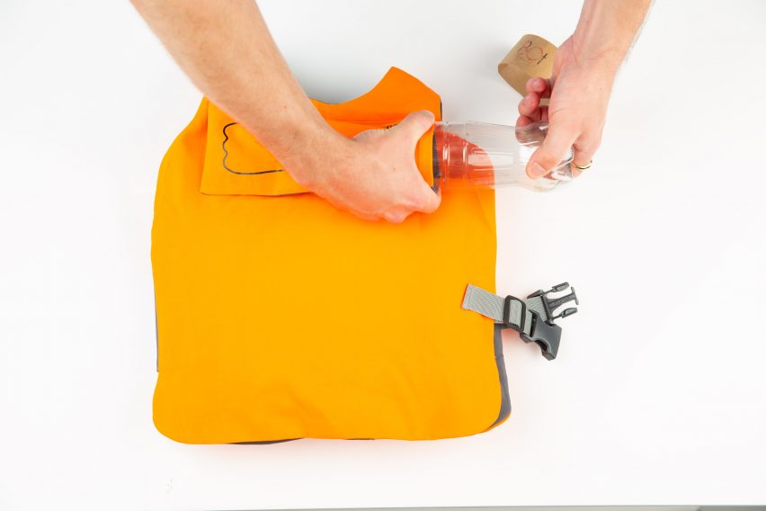 Photo of a pair of hands inserting an empty plastic bottle into the back of an orange vest
