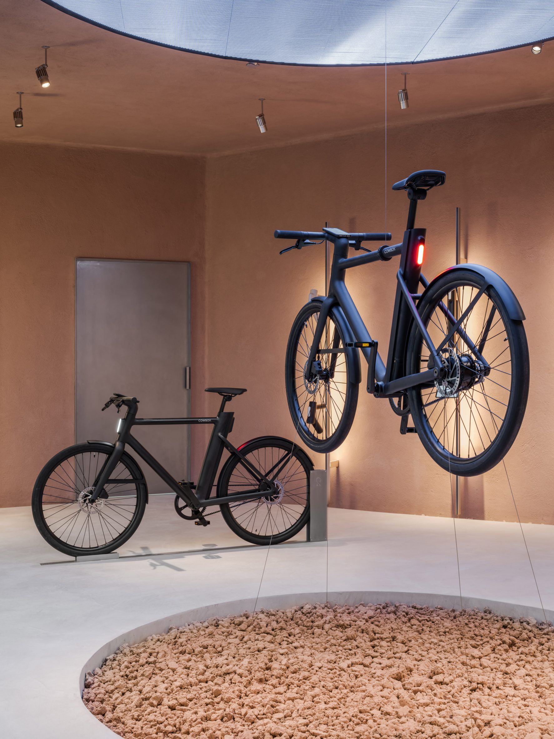 Electric bikes by Cowboy suspended over earth pit in store by Ciguë