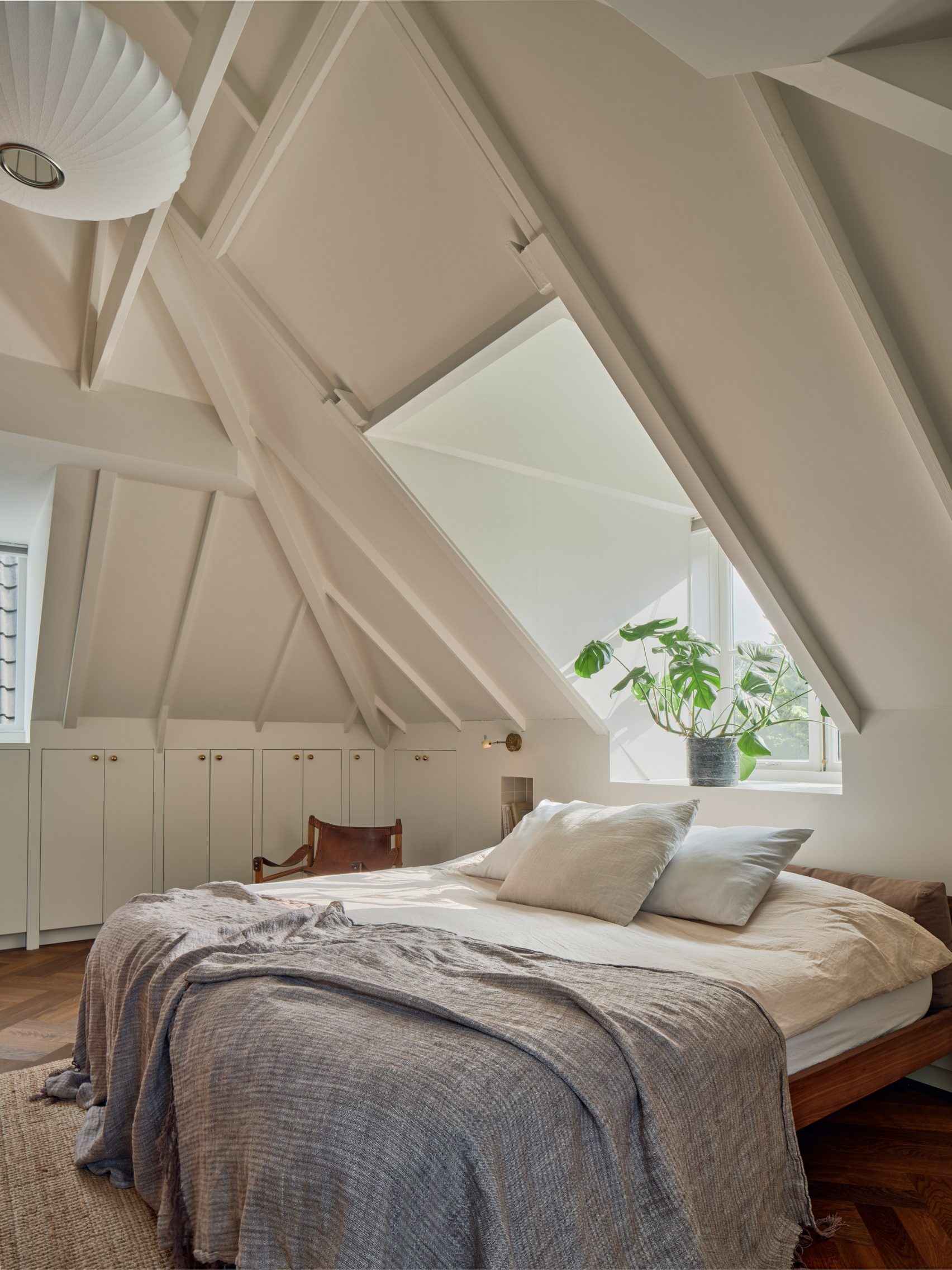 Bedroom with white walls and a green plant in the window