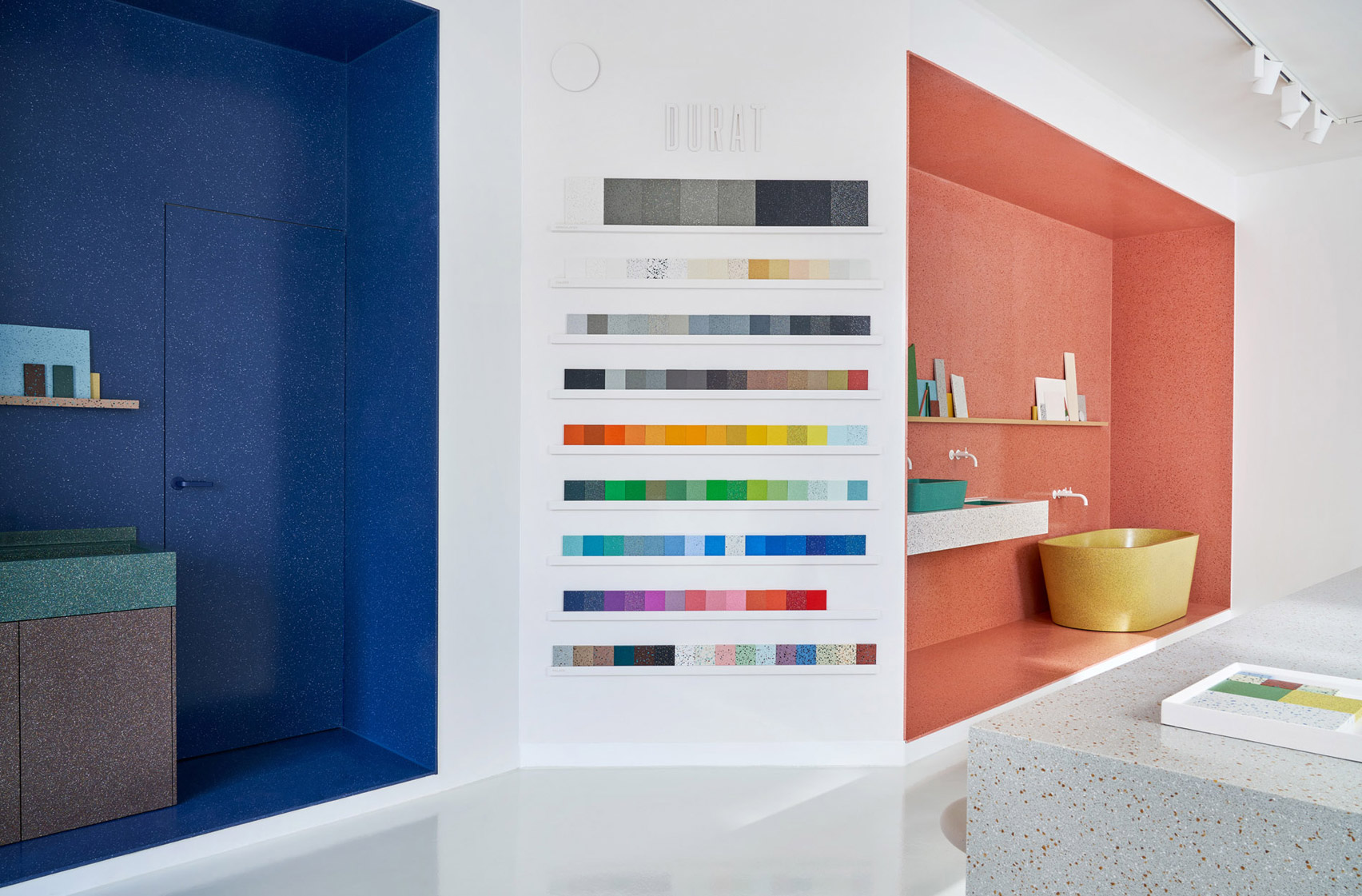 Photo of Durat showroom showing central island, three colourful displays and a wall of samples