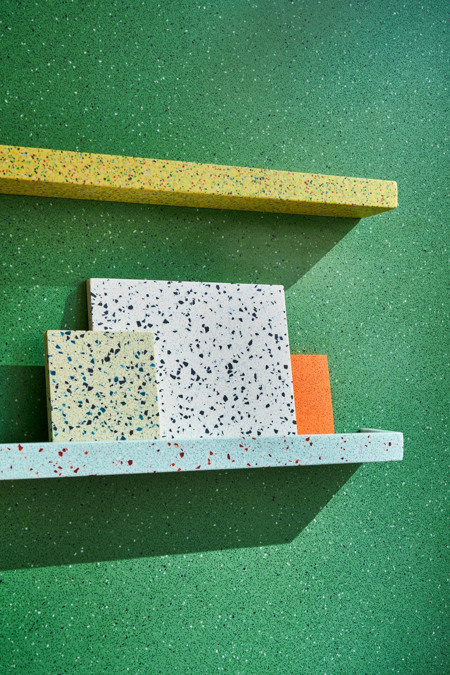Durat material samples on a shelf in front of a green wall