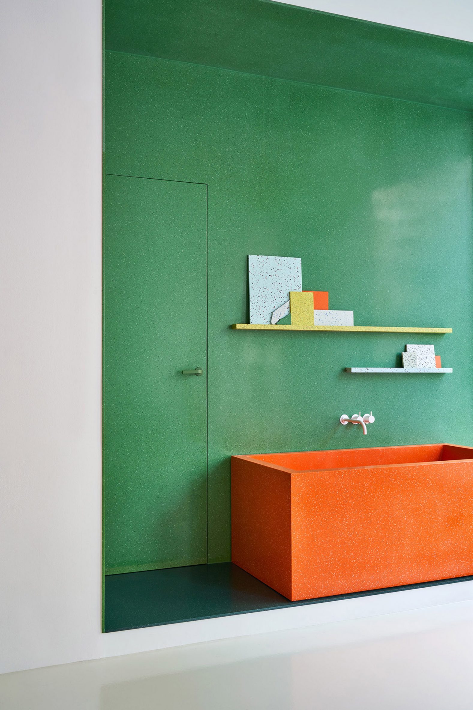 Orange wash trough against a green wall in the Durat Helsinki showroom