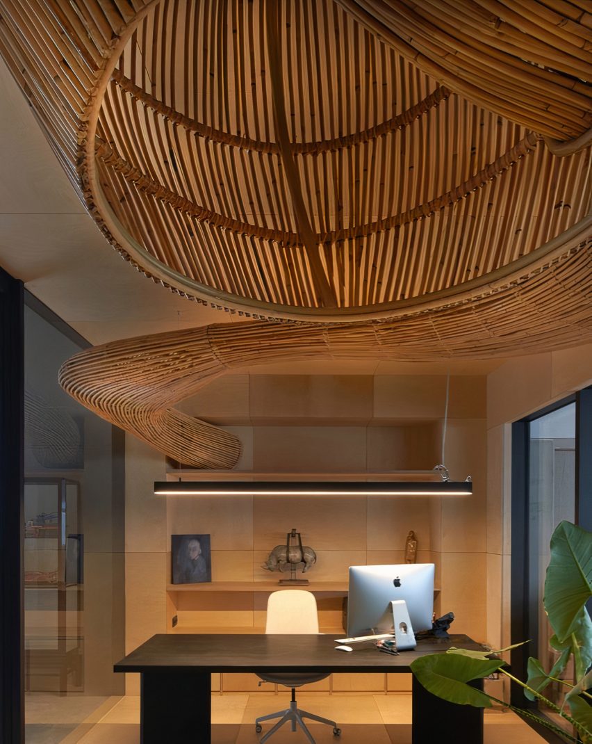 Office desk underneath a curved rattan sculpture by Enter Projects Asia