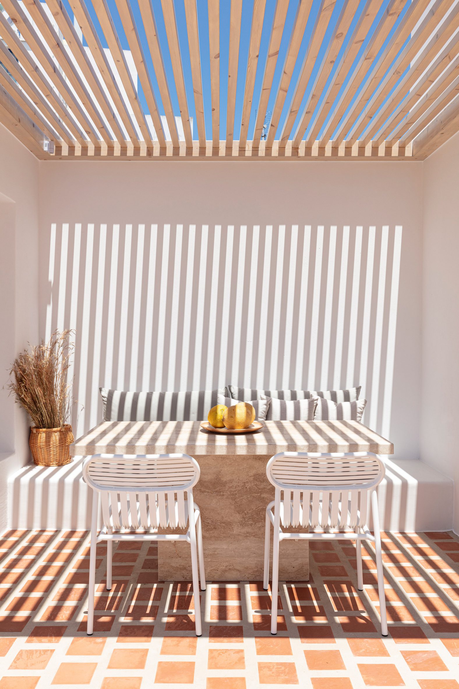 Wooden beams create shadows over the dining area on the terrace