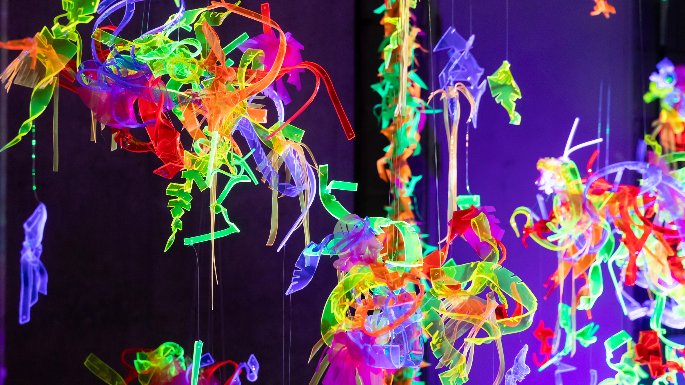 Brightly coloured fluorescent shapes hanging in blacklight-lit space