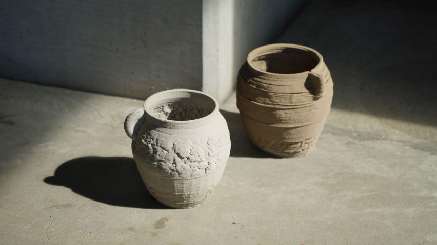 Photograph showing white and beige handled urns on stone floor