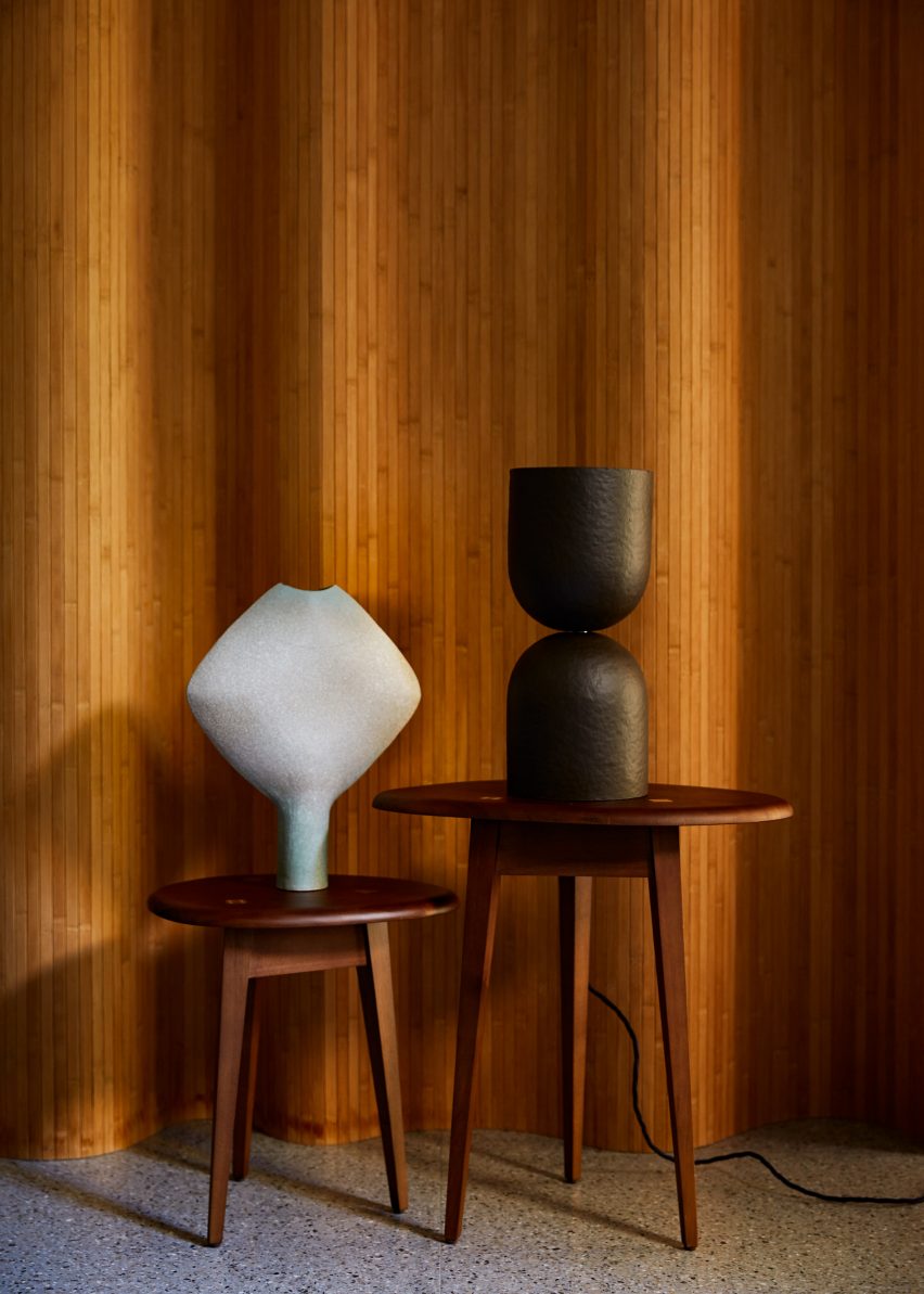 Sculptural black and white lamps on small tables against a curved wall