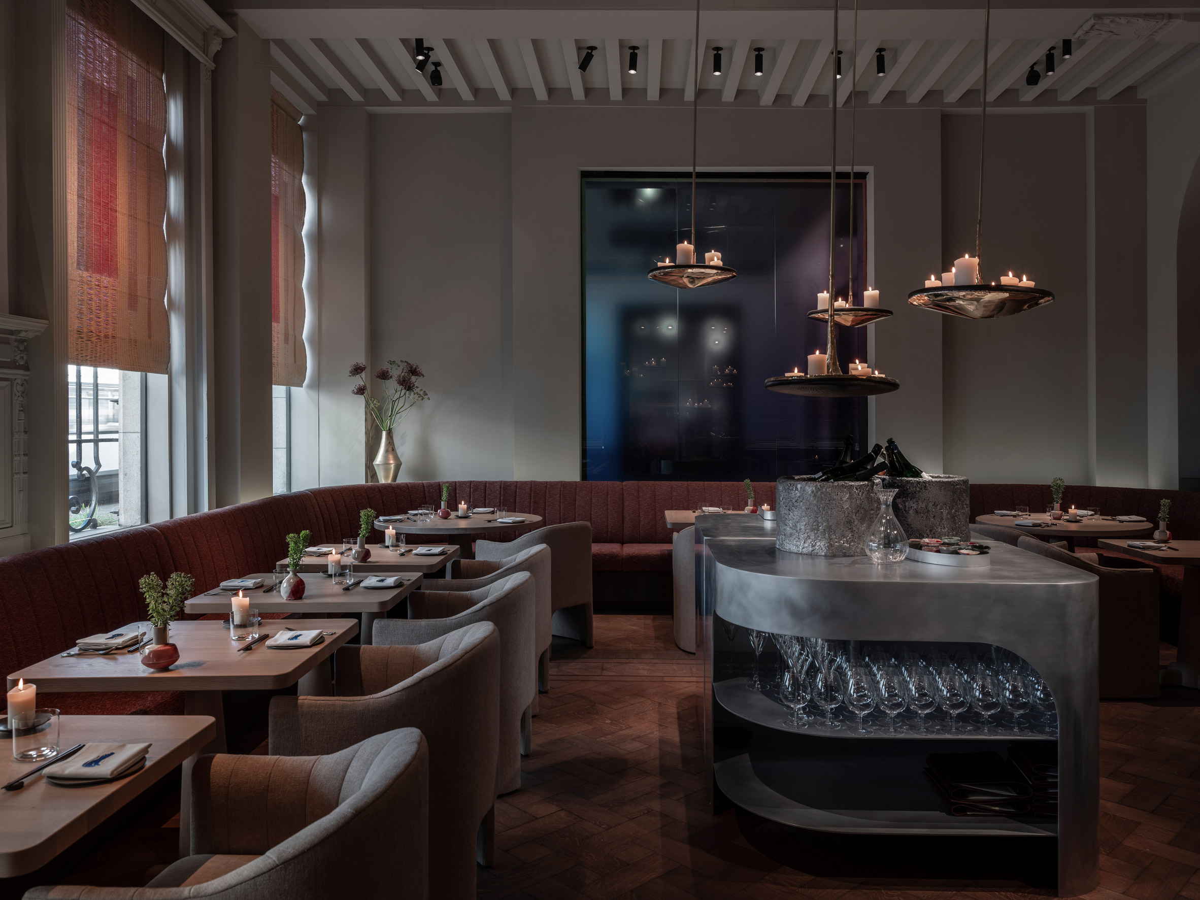 Dimly lit restaurant with fabric-coated seating and hanging candles