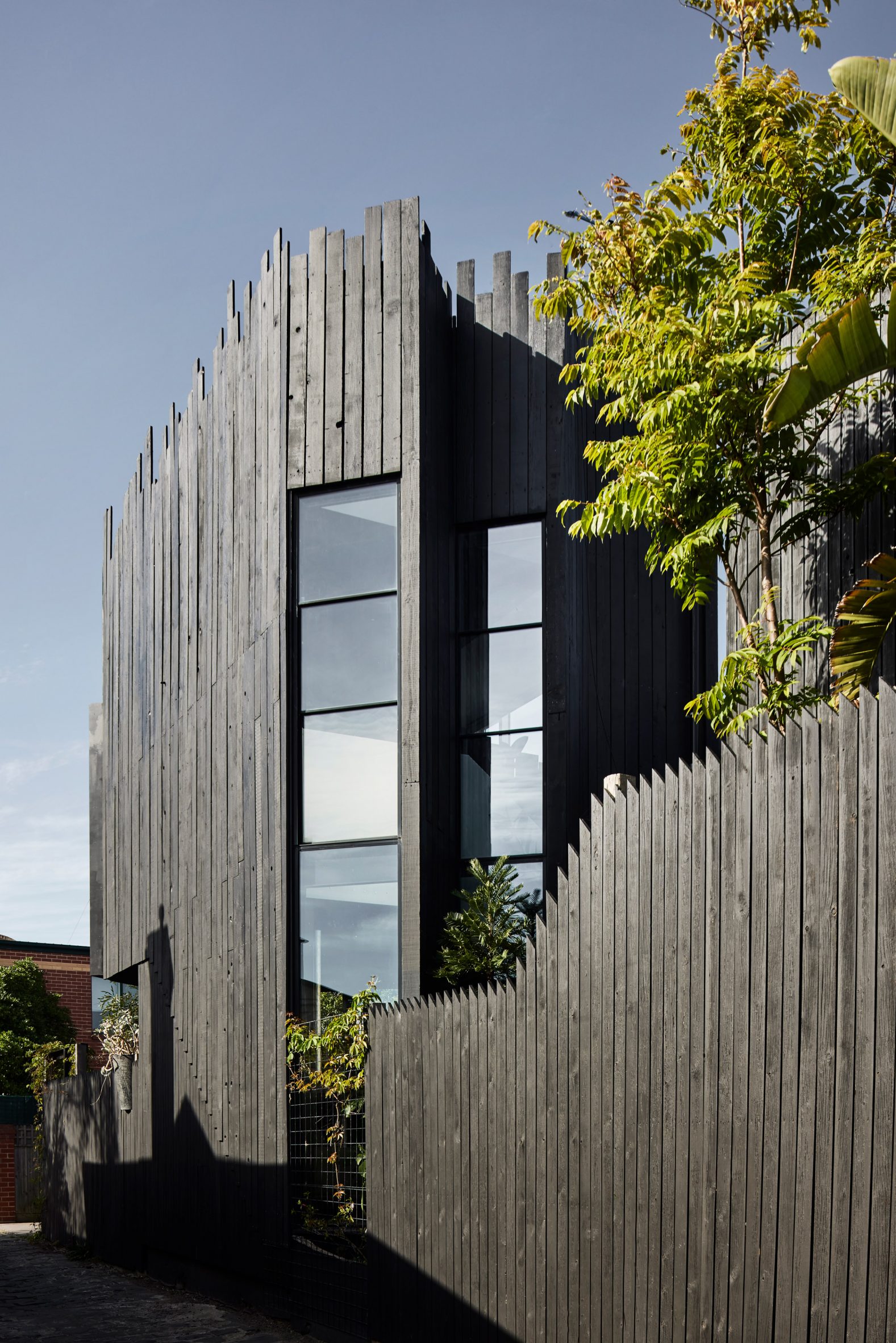 Rectangular windows punctuate the black timber facade at Host House