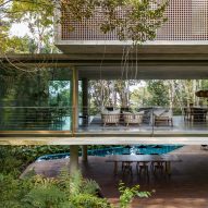 First floor of Casa Azul by Studio MK27 with open glass doors providing through views of the forest