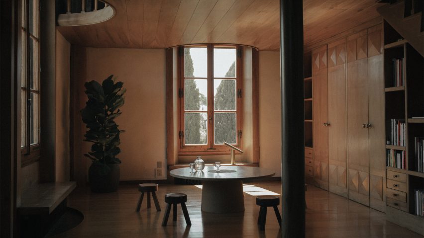Low wooden stools around a dining table in wood panelled kitchen of Villa Medicea di Marignolle apartment by Albert Moya