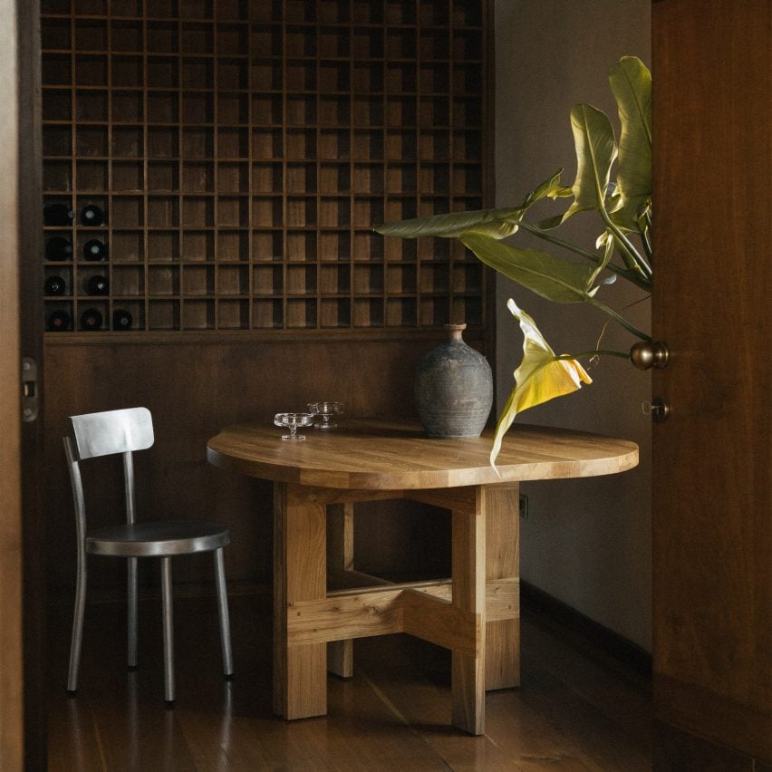 Wooden table and metal chair in front of wine rack in Villa Medicea di Marignolle apartment by Frama