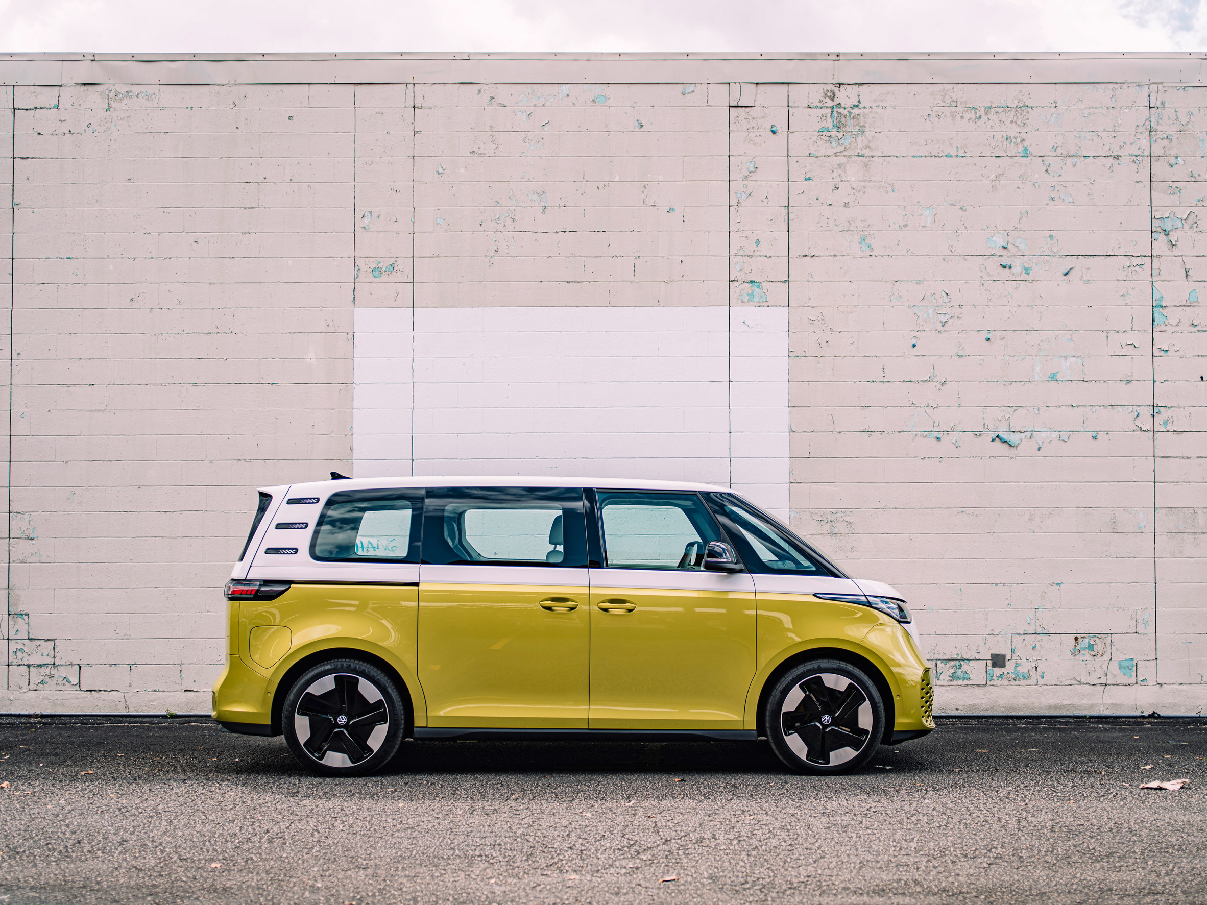 Yellow Volkswagen minivan parked by a white wall