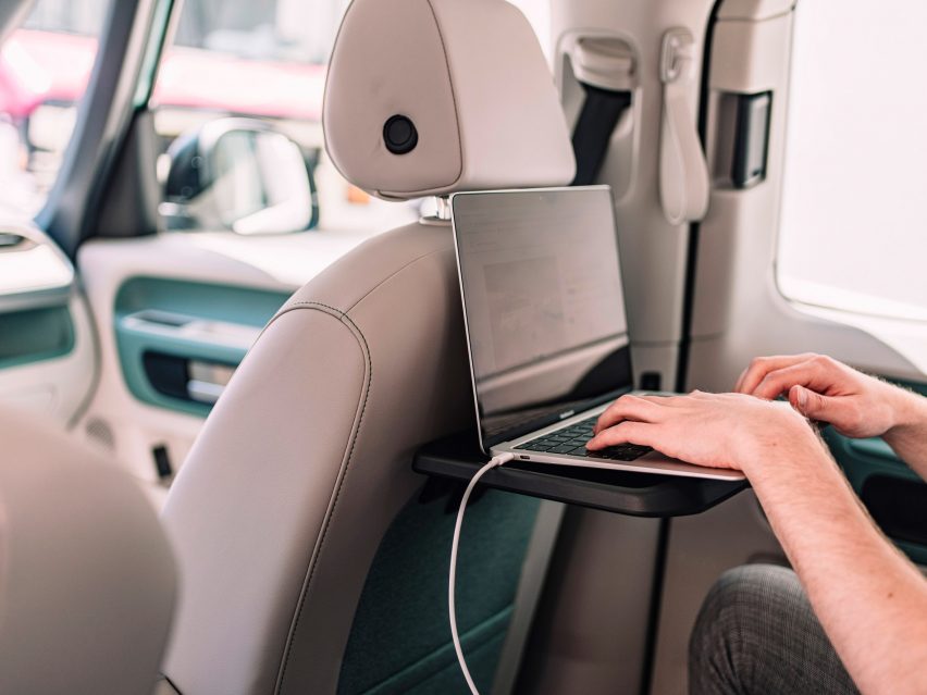 Person working on a laptop on a fold-down table in the backseat of the van