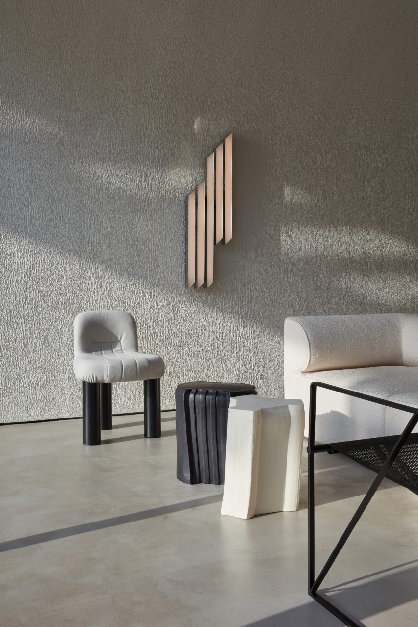Seating area of a coffee shop in Dubai with black and white furnishings and a wall light by VSHD