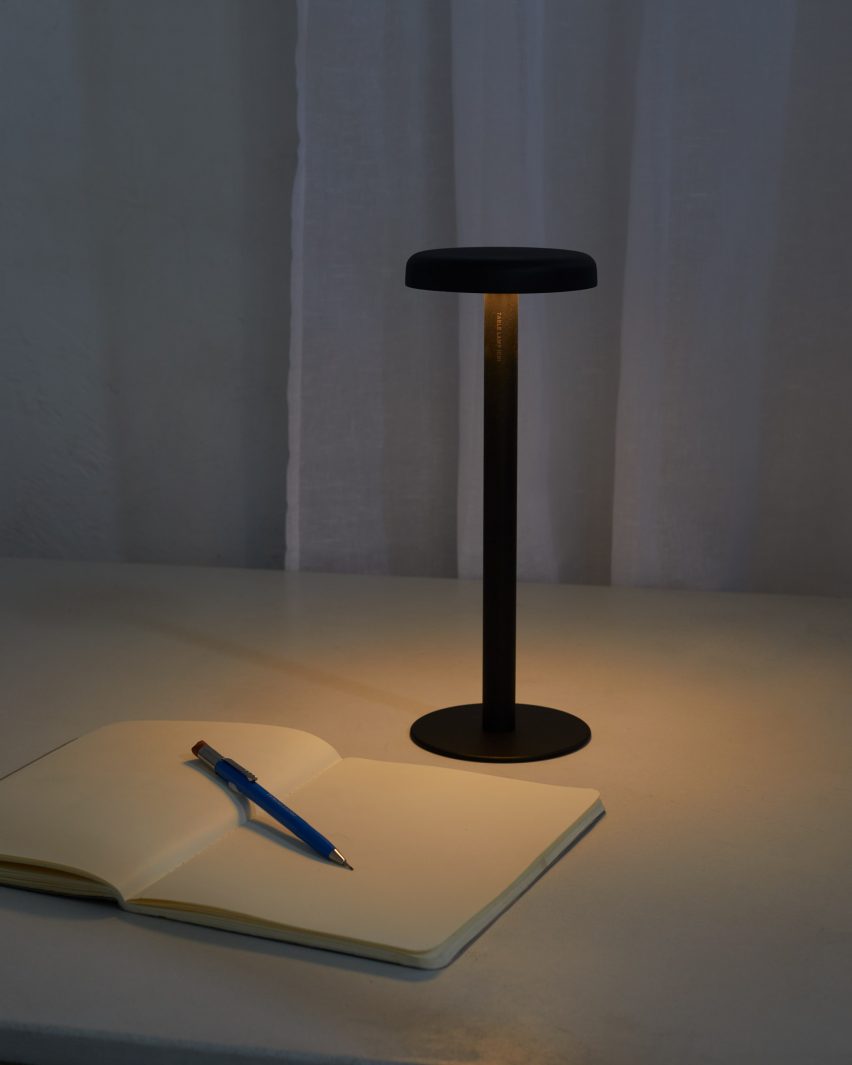 Black desk lamp shining on a notebook and pen