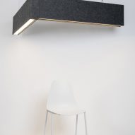 Photograph showing white chair beneath L-shaped lighting fixture on ceiling