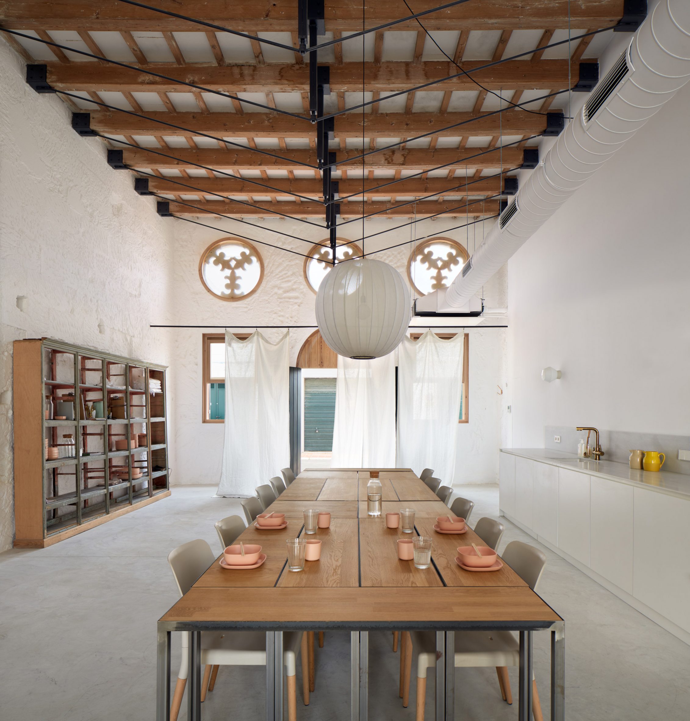 Dining area of creative retreat designed by Anna Truyol and Emma Martí with long wooden table