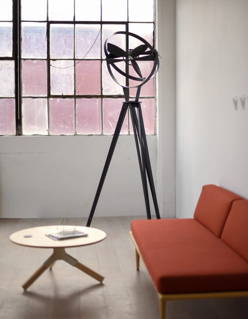 Photograph showing pedestal fan next to orange sofa in an industrial setting