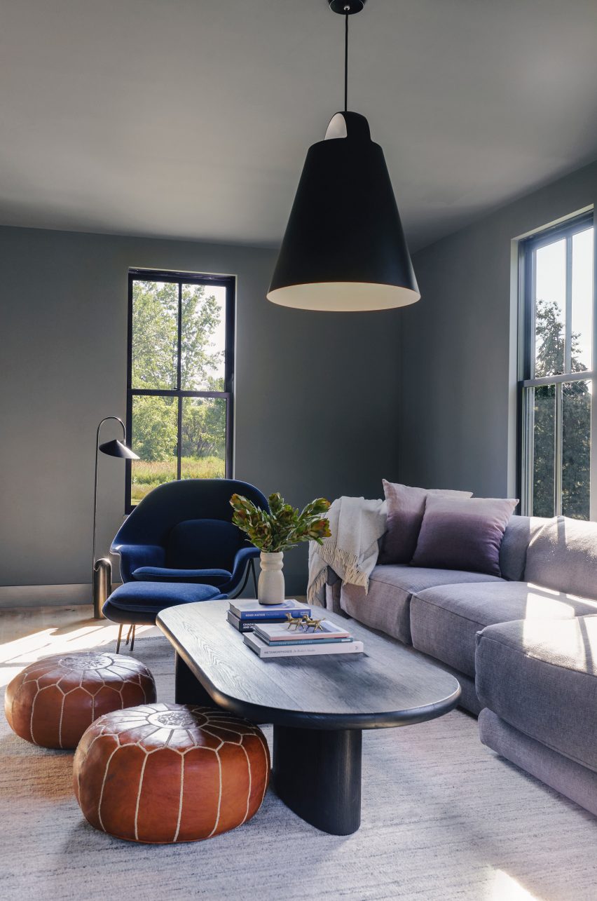 Grey-toned living room with orange and blue accents, purple sofa, and black hanging light in homestead