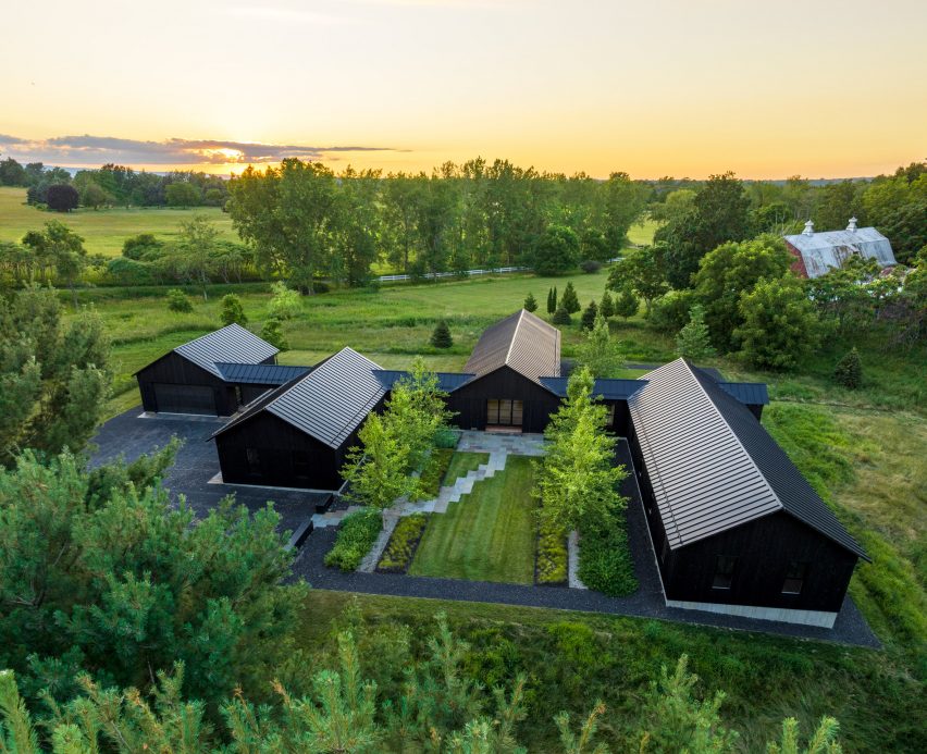 All-black farmhouse named Homestead by Birdseye between trees on lakeside site in Vermont