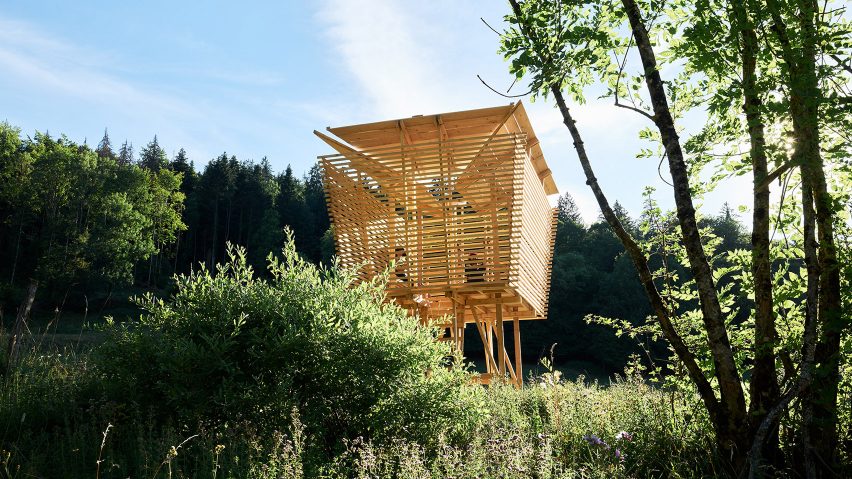 A wooden square shaped cabin in a field