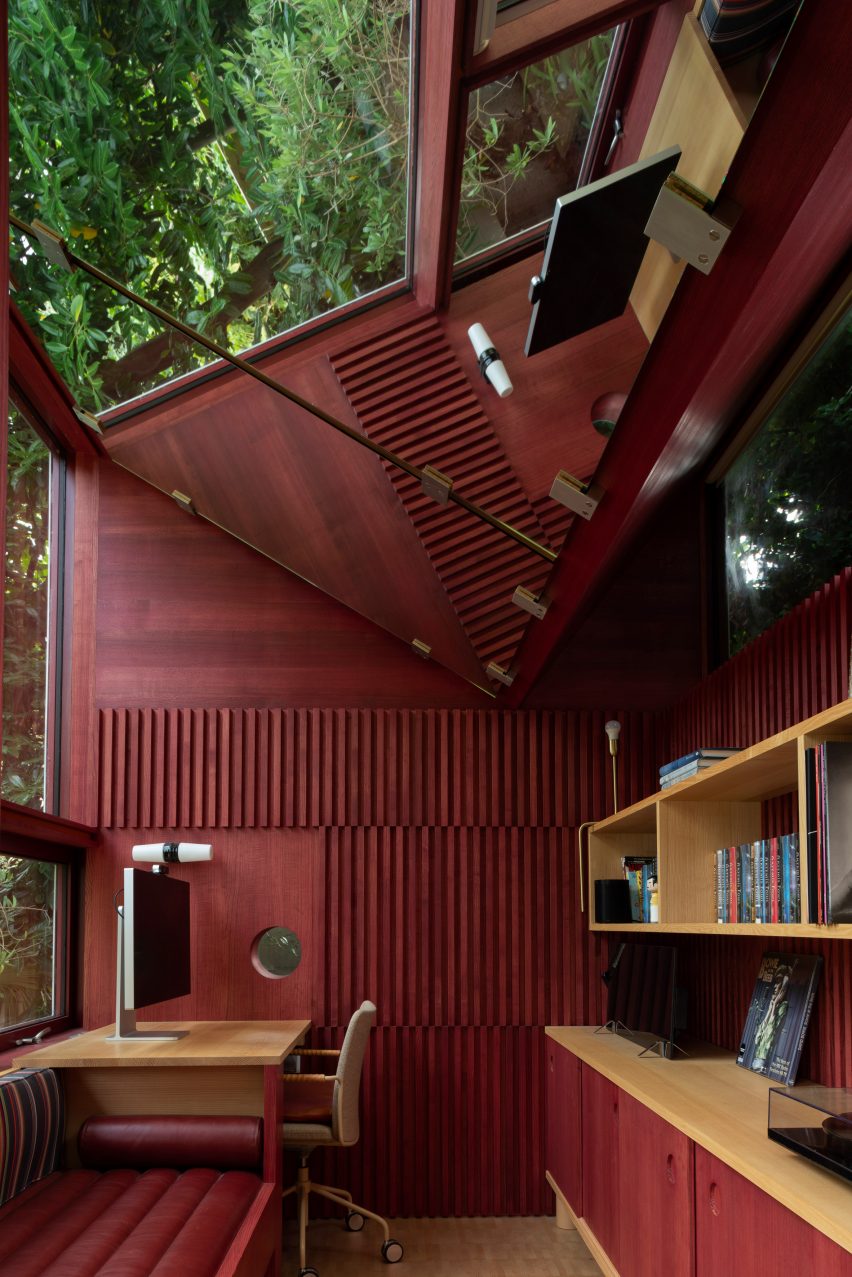 Mirrored V-shaped ceiling at top of red interior of garden hut by Clancy Moore Architects